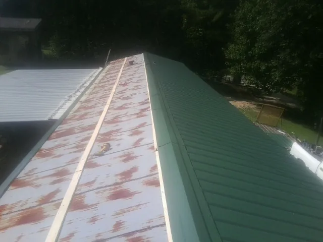 Old rusted panels beside newly installed green metal roofing — Wind Damage Roof Repair by Roofing Brothers in Browns Mills