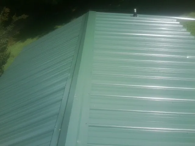 New green metal panels meeting at the ridge of a roof — Flat Roof Repair work by our crew in Browns Mills
