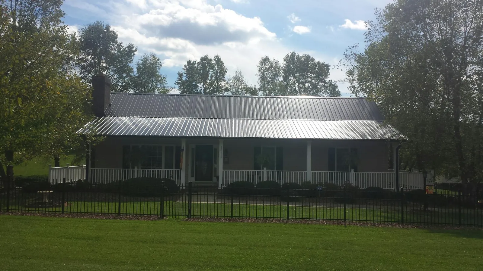 Gray metal roof on a brick ranch with a full width front porch — Gutter Guard Installation work by our crew in Browns Mills