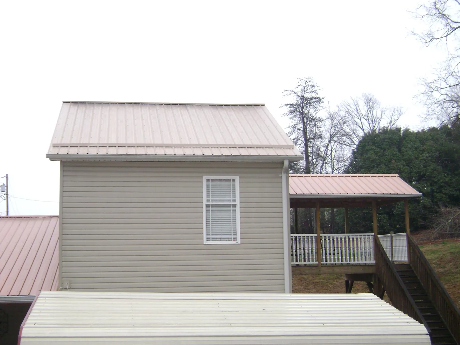 Tan metal roofs on a two story addition and attached porch, from a Roof Replacement job in Browns Mills