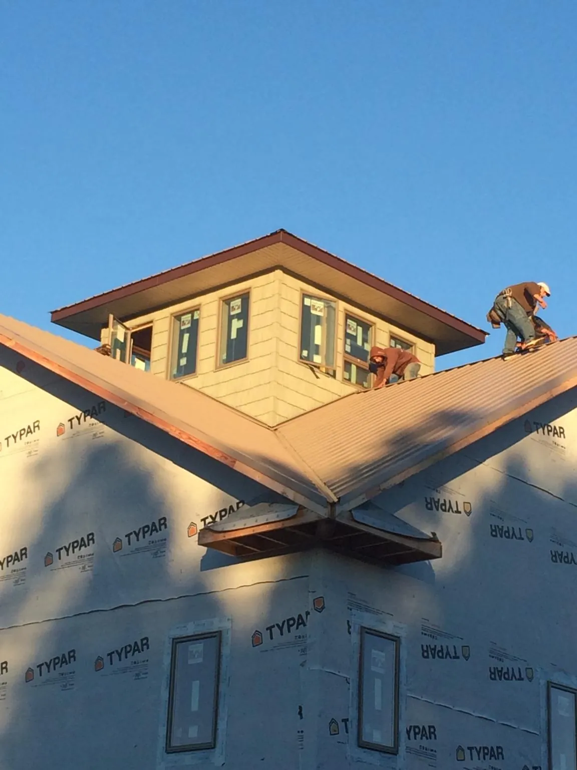 Roofers working around a rooftop cupola on a new metal roof at sunset — Roof Waterproofing in Browns Mills by Roofing Brothers